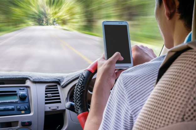 Man looks at phone whilst driving