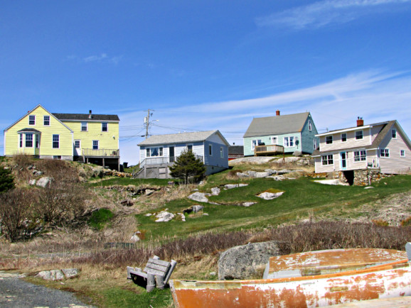 four multi-coloured wooden cabins sit atop a small hill