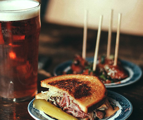 a toasted sandwich next to a pint of beer
