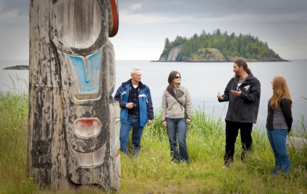 tour group looking at a first nation's totem pole