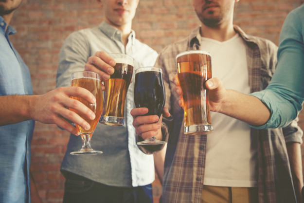 group of men clink glasses of beer