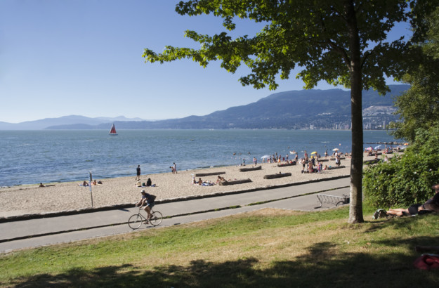 cyclist riding past beachgoers in Stanley Park, Vancouver