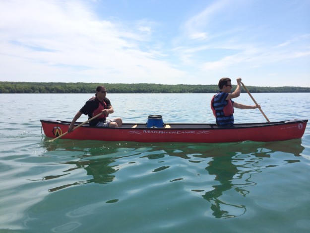 two men row a canoe
