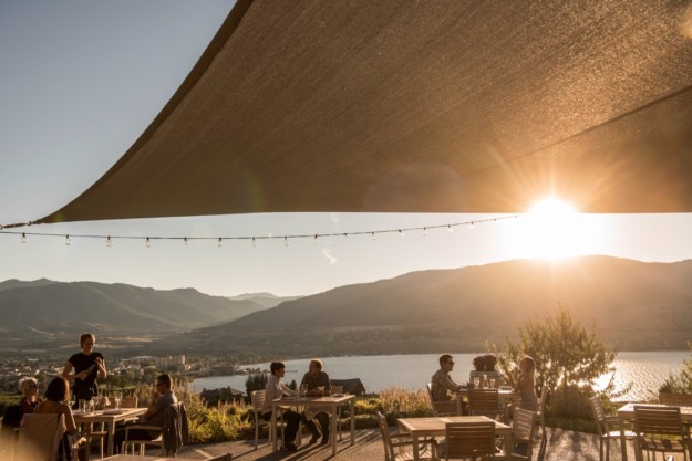 Patrons of The Vanilla Pod Restaurant at Poplar Grove winery enjoy dining on the patio with views of Okanagan Lake and Penticton, BC.