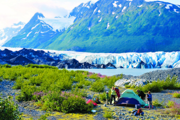 family sets up tent in front of glacier