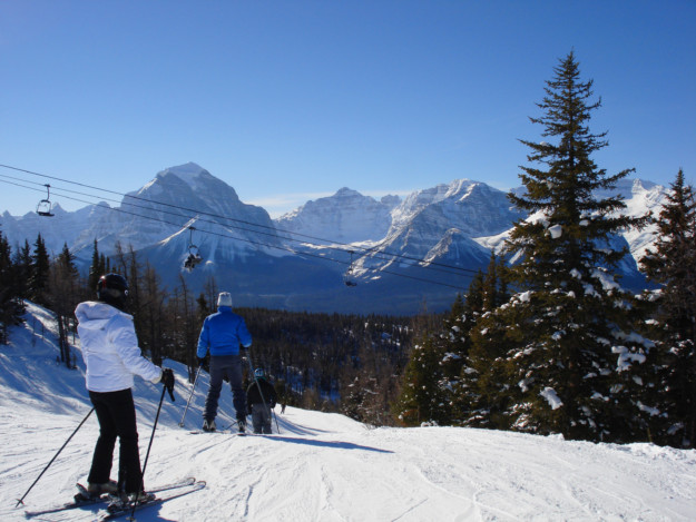 three people ski down the slopes in the Rocky Mountains