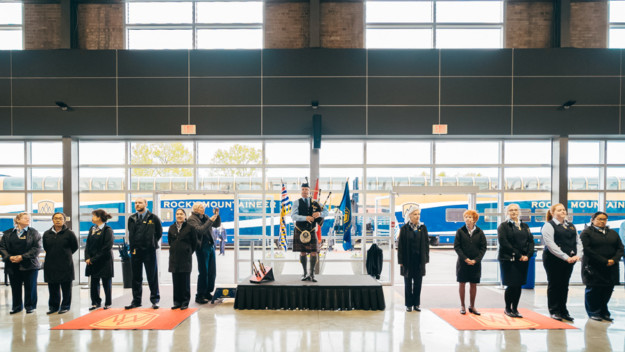 a man playing bagpipes and a team of staff wait to greet customers