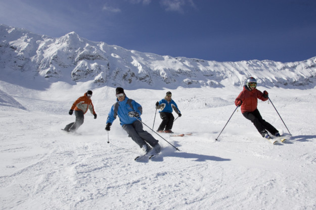 four skiers slalom down a slope