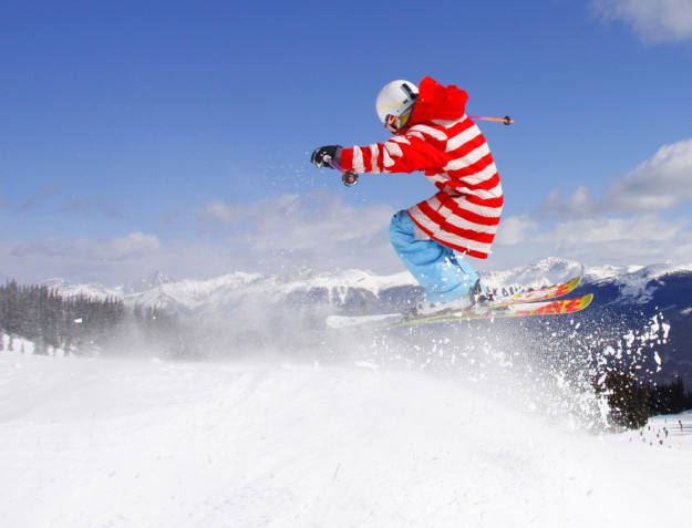 skier in a red and white striped coat takes a jump