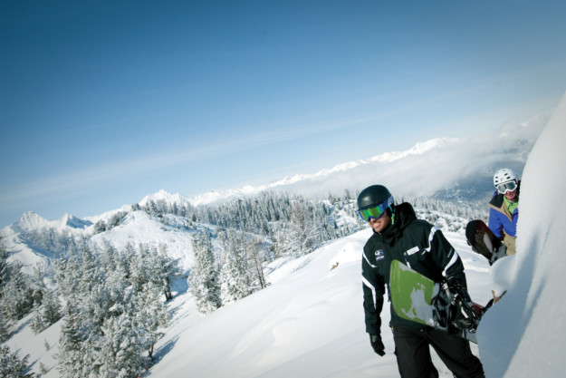 two snowboarders hike up a snowy mountain