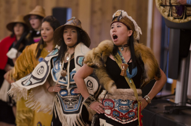 first nations people in traditional clothing sing