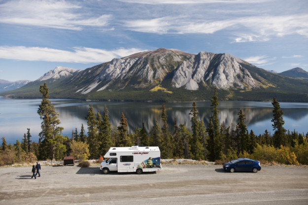 a motorhome is parked at a scenic viewpoint with a lake and mountain in the background