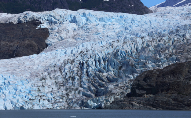 a steep blue and white glacier stretches up a hill