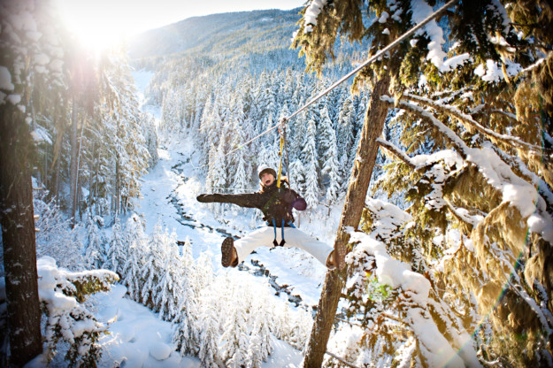 a women screams as she ziplines through a snowy forest