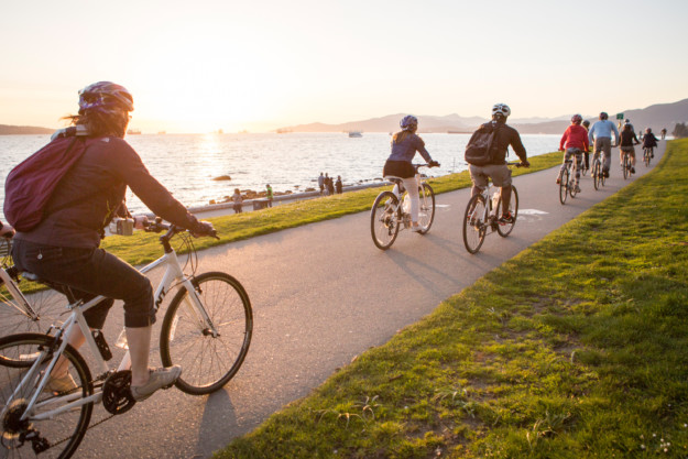 a group of cyclists bike along the seawall in Stanley Park, Vancouver