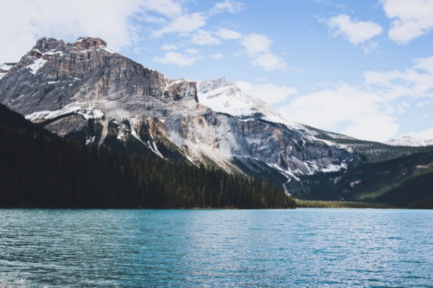 a snow capped mountain stands in the background above a lake