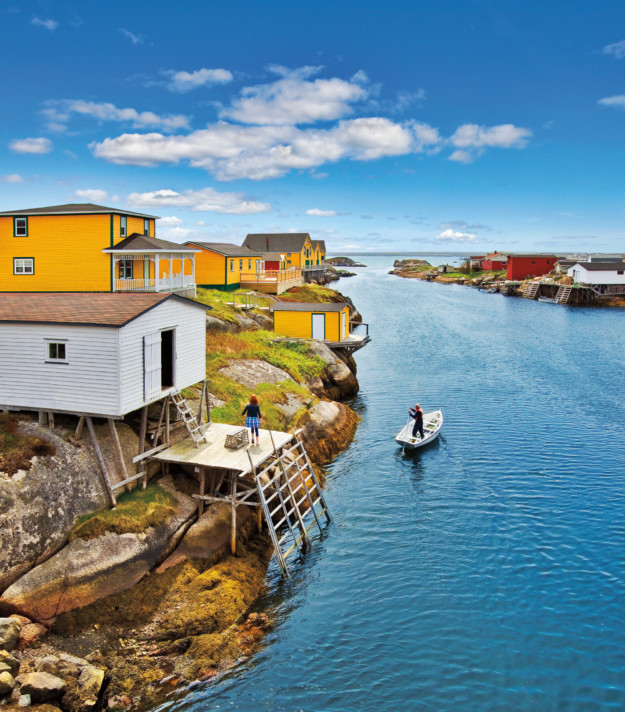 colourful wooden huts on stilts sit next to an inlet of water
