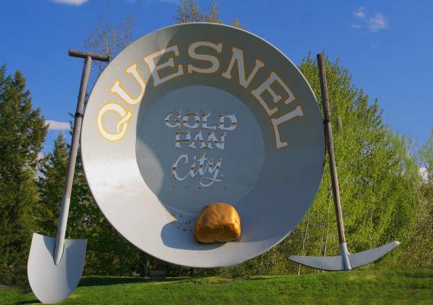 a novelty Quesnel sign reads gold pan city flanked by a shovel and pick axe