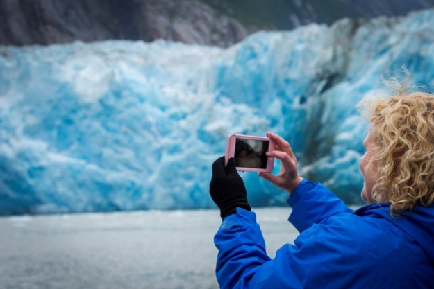 A woman photographs a glacier in Alaska