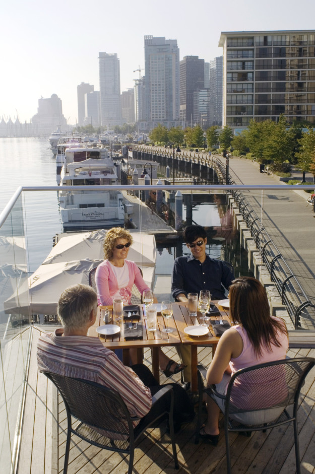a group of four sit at a restaurant table on the Vancouver waterfront