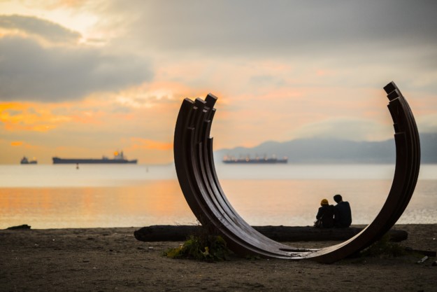 a couple enjoy the sunset with an art sculpture in the foreground