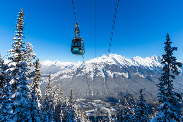 a gondola ascends over a snowy mountain scene