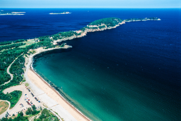 a golden sandy beach in the foreground with a thin peninsula stretching out to sea