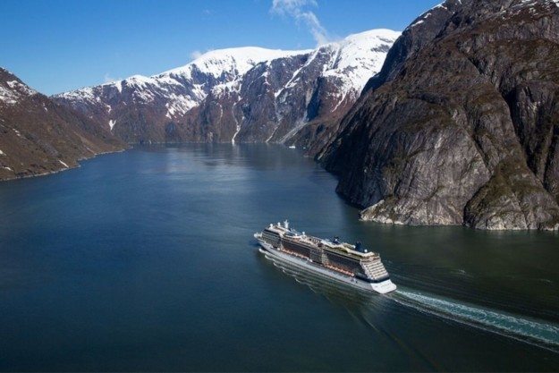 a cruise sails through a narrow passage with mountains on either side