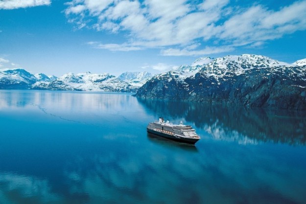 a cruise ship sits on crystal blue water with snow-capped mountains in the background