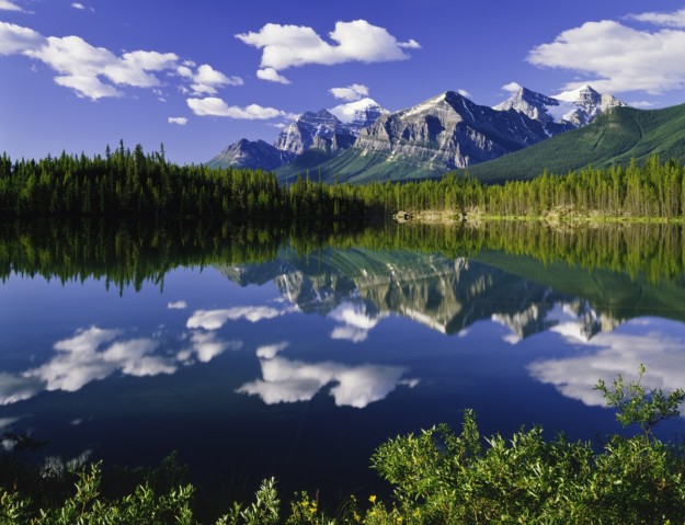 a mountain in the background is reflected perfectly in a lake
