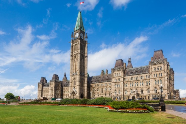 the exterior of the Canadian parliament buildings with a green lawn in front