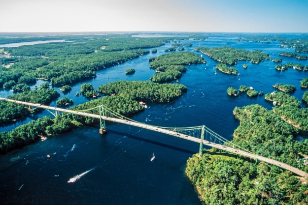 a suspension bridge cross over blue water across green forests