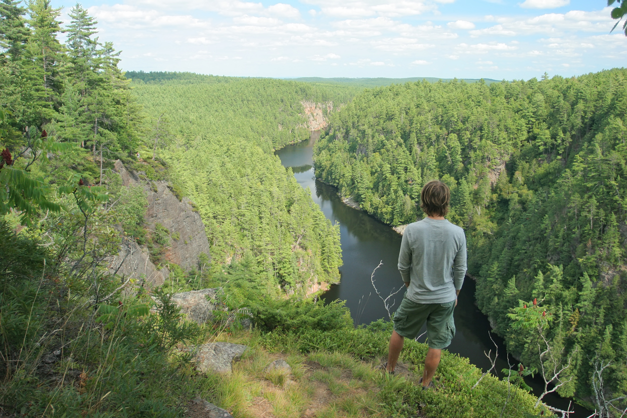 A man standing on a cliff overlooking a river