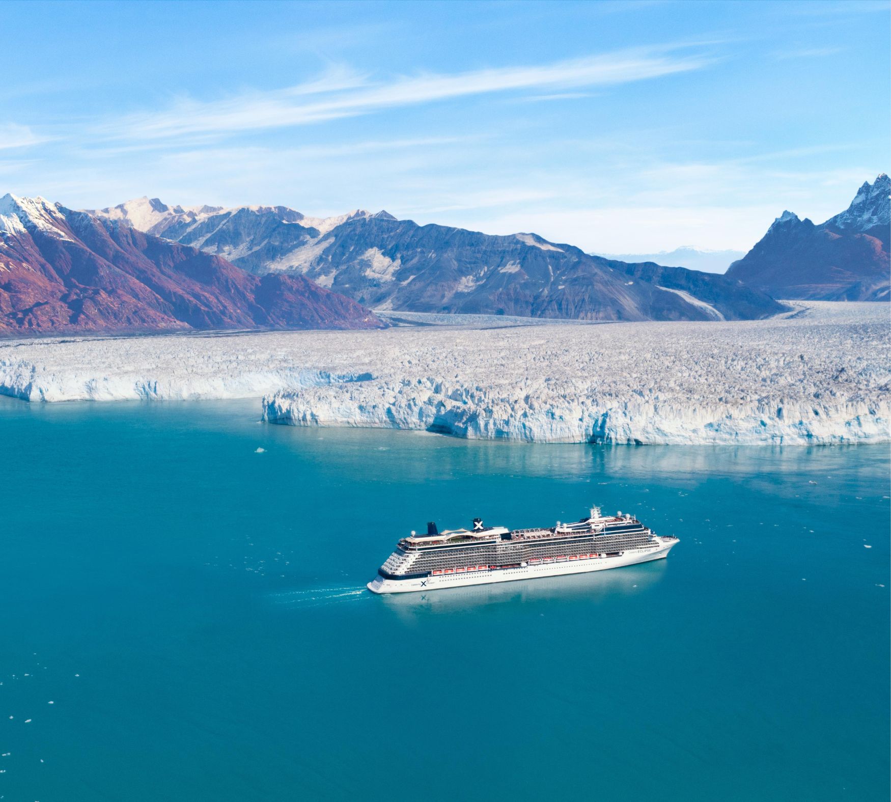 a cruise ship sits in the foreground with a giant glacial shelf in the background