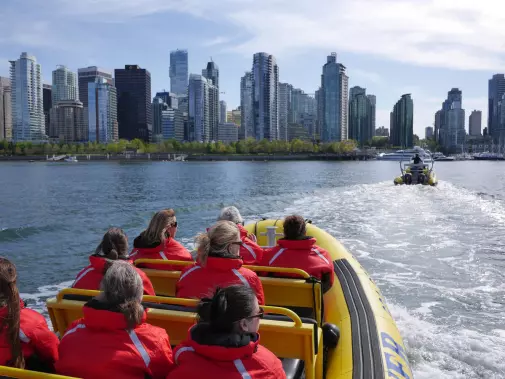Touring Vancouver city's waterfront by speedboat, with modern skyscrapers in the background.