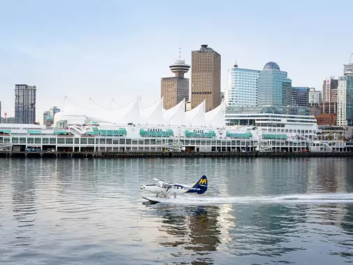A seaplane taking off in front of Vancouver's downtown skyline, and the distinct white sails of Canada Place.
