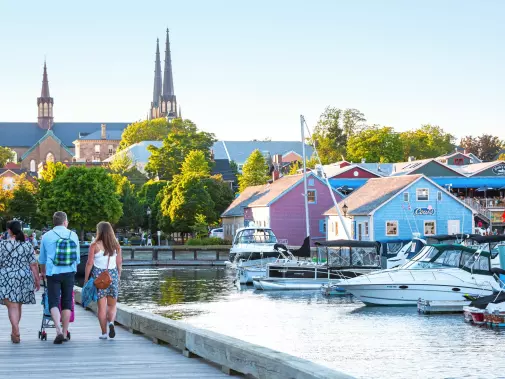 The scenic waterfront boardwalk of Charlottetown with colorful buildings, and moored boats.