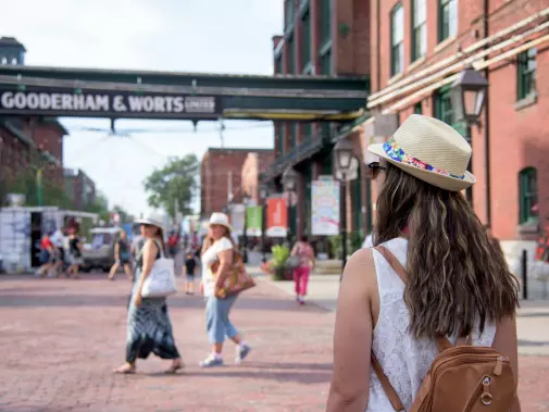 Visitors in a bustling distillery district street near the historic Gooderham & Worts sign