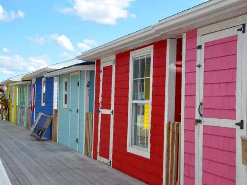 A row of colorful beach huts under a clear blue sky on the wooden boardwalk of Sydney in  Cape Breton.